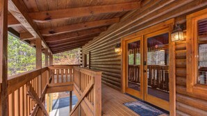 A wooden cabin with a covered porch, a staircase, and a glass door with a metal gate. - Secluded Hideaway (Pigeon Forge)