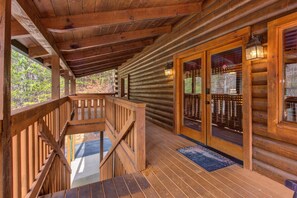 A wooden cabin with a covered porch, a staircase, and a glass door with a metal gate. - Secluded Hideaway (Pigeon Forge)