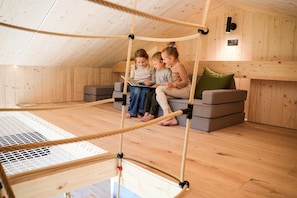 A wooden interior with a trampoline, a sofa, and a child playing.