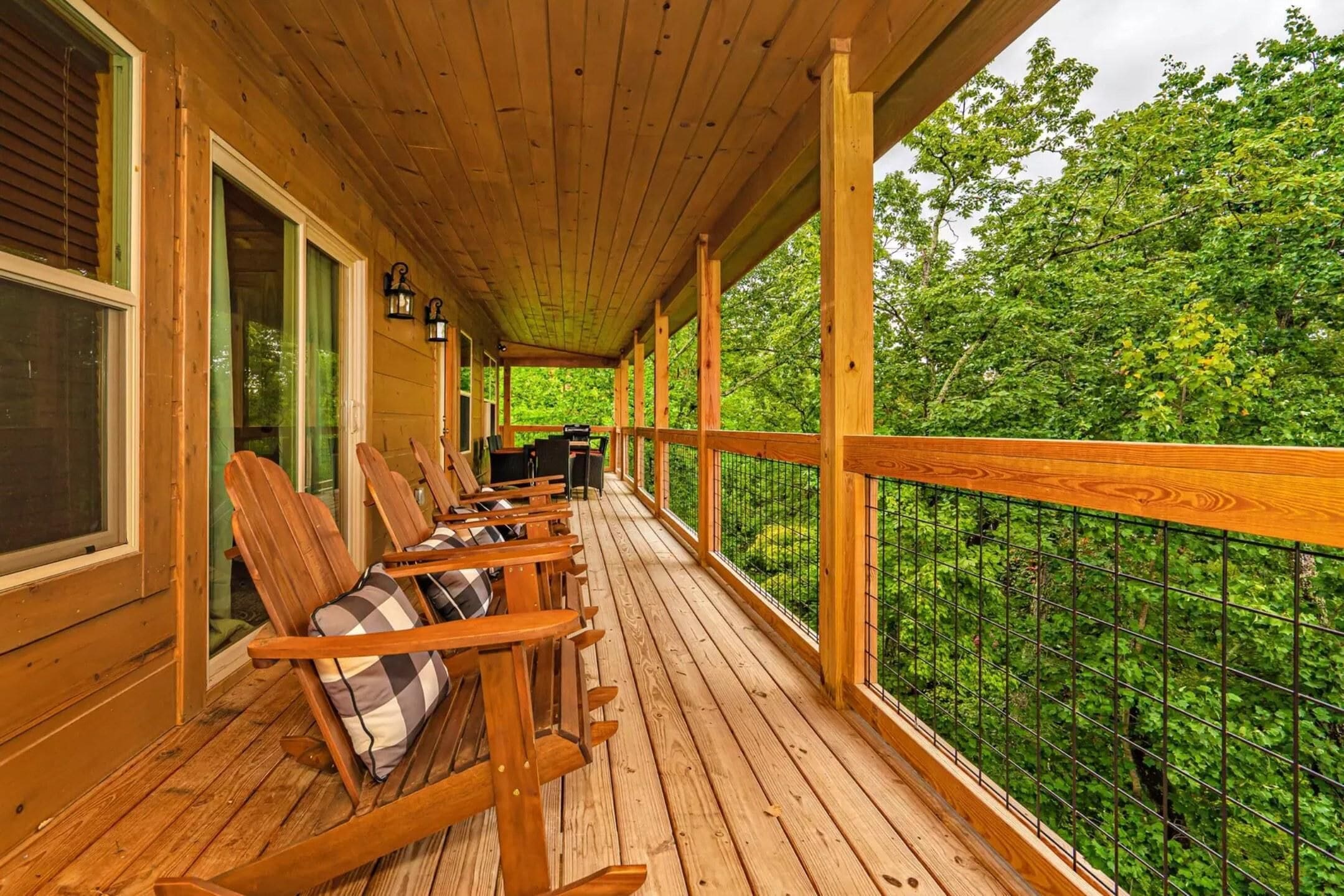 A wooden deck with rocking chairs and a view of a forest.