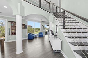 Un vaste espace de vie comprenant un escalier, un ventilateur de plafond et une vue sur l’extérieur.