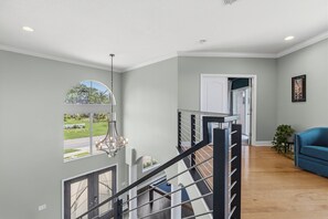 Un intérieur spacieux avec un escalier, une vue par la fenêtre et un canapé bleu.