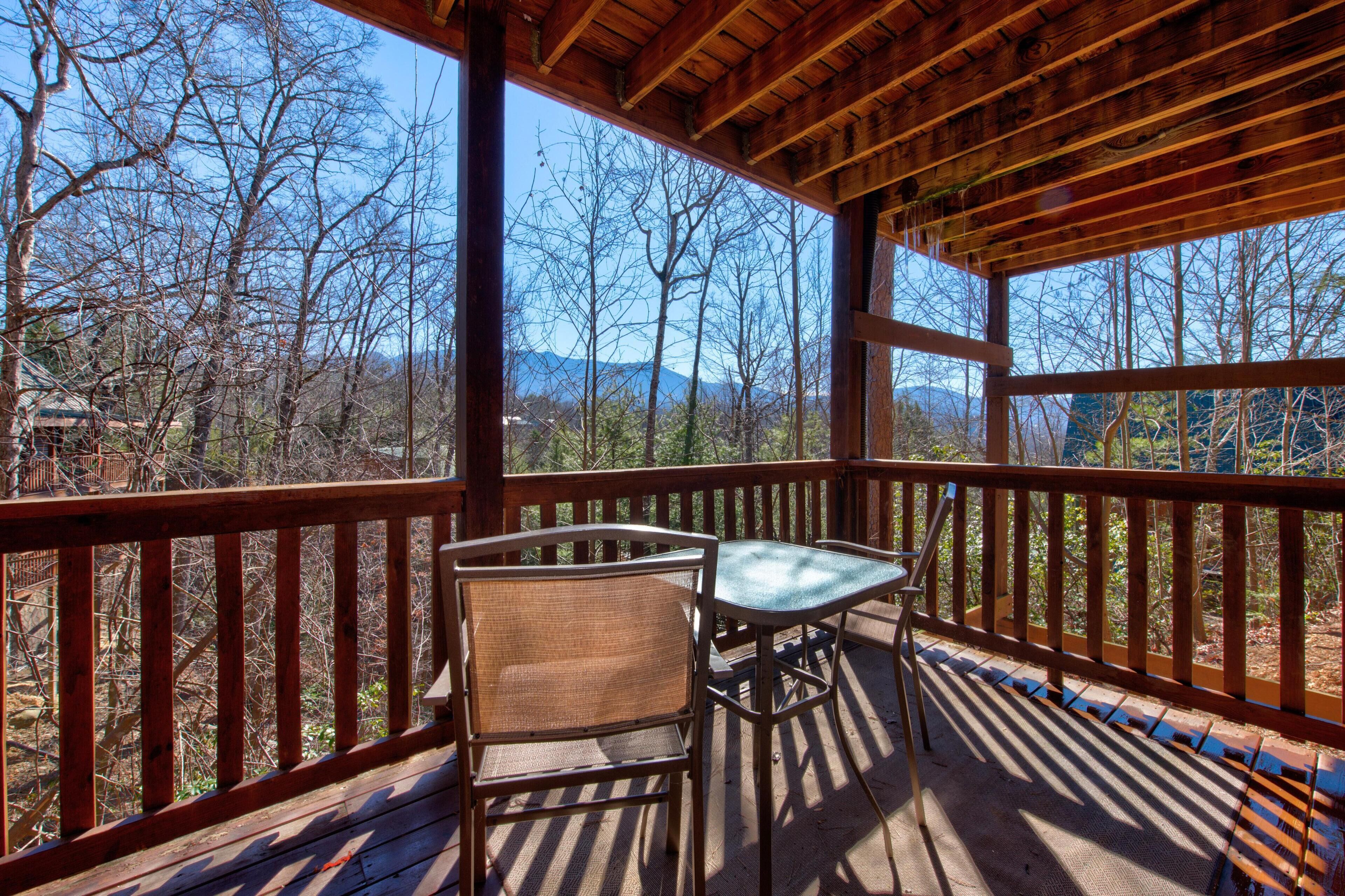 Une terrasse en bois avec une table et des chaises, offrant une vue sur un paysage montagneux.