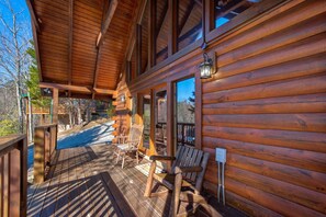 A wooden cabin with a porch, wooden chairs, and a bench. - A Grand Getaway (Gatlinburg)