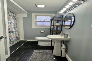 A bathroom with a toilet, sink, and mirror. - Walk to Beach & Downtown -- Summer Getaway (Manistee)