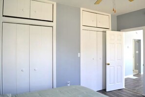 A bedroom with a bed, two wardrobes, a door, and a ceiling fan. - Walk to Beach & Downtown -- Summer Getaway (Manistee)
