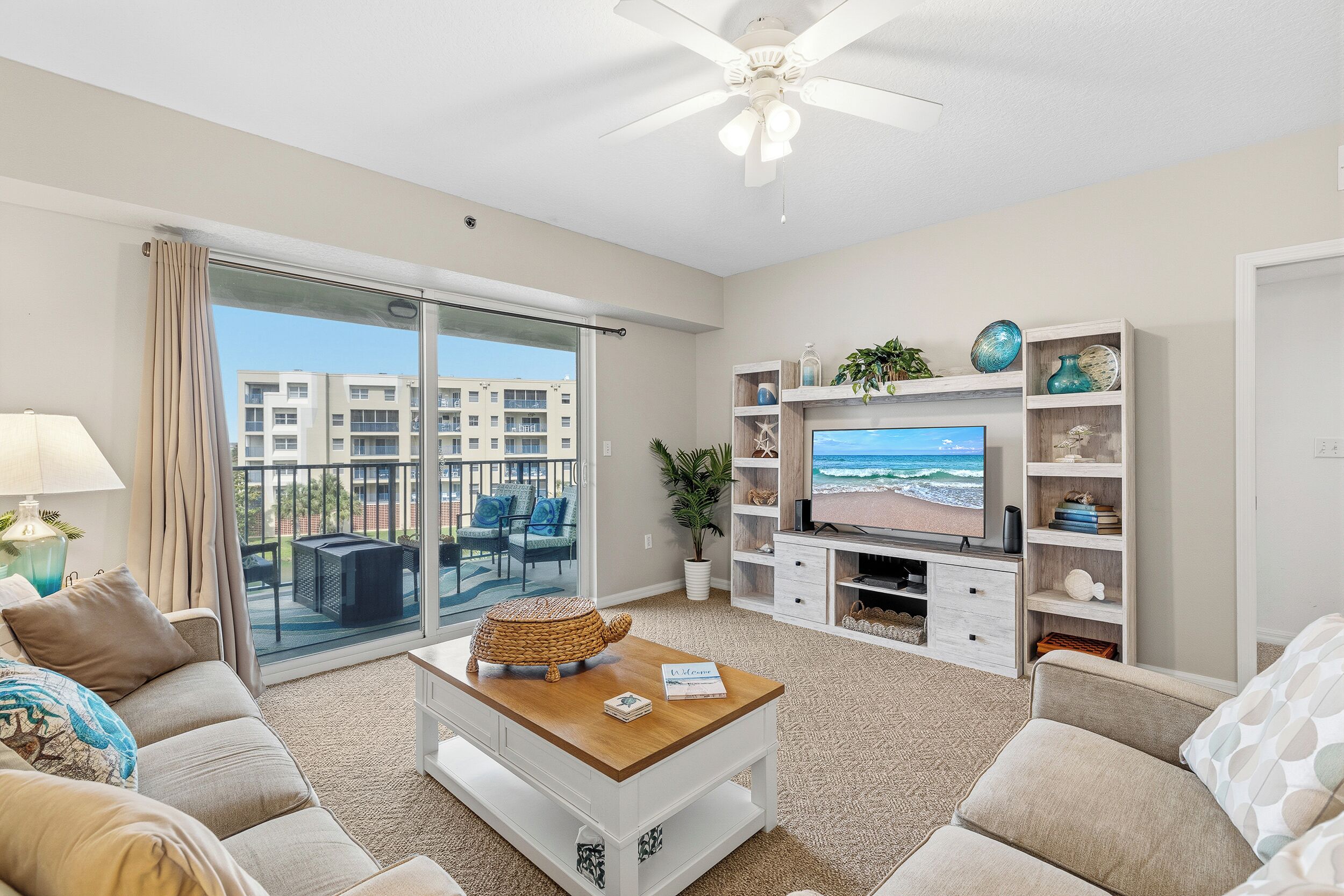 A living room with a sofa, coffee table, TV, and a balcony with a view.