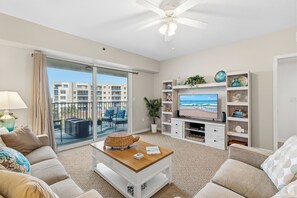 Ein Wohnzimmer mit einer Couch, einem Couchtisch, einem Fernseher und einem Balkon mit Blick.