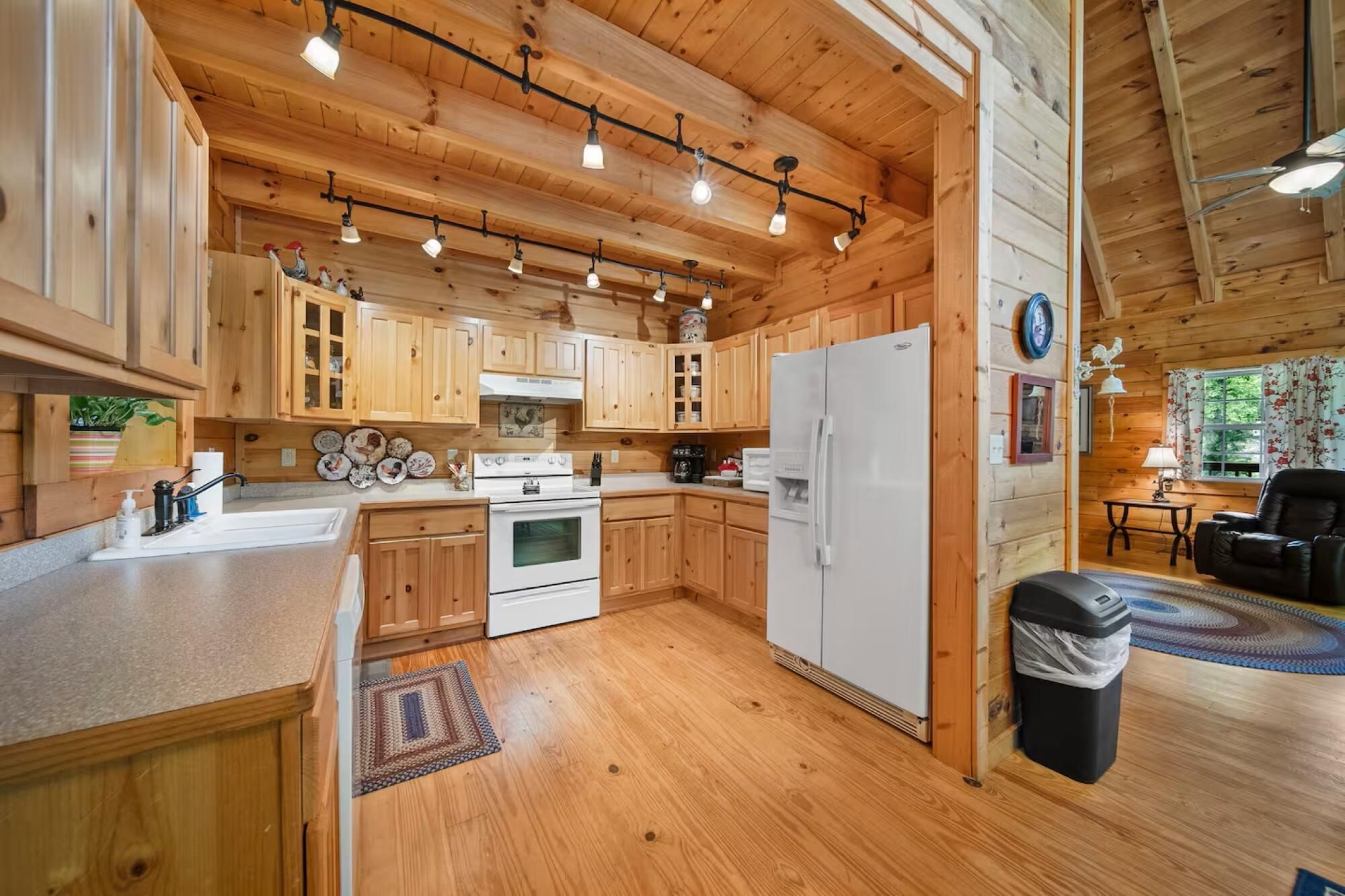 A wooden cabin interior with a kitchen, dining area, and a living room.