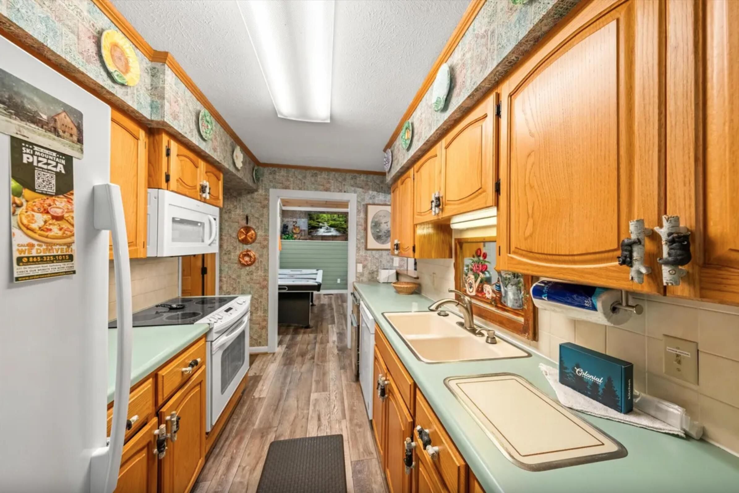 A compact kitchen with wooden cabinets, a microwave, a stove, and a sink.