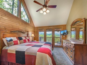 A bedroom with a bed, a dresser, a television, a ceiling fan, and a balcony with a view. - Eagles Point Lodge (Gatlinburg)
