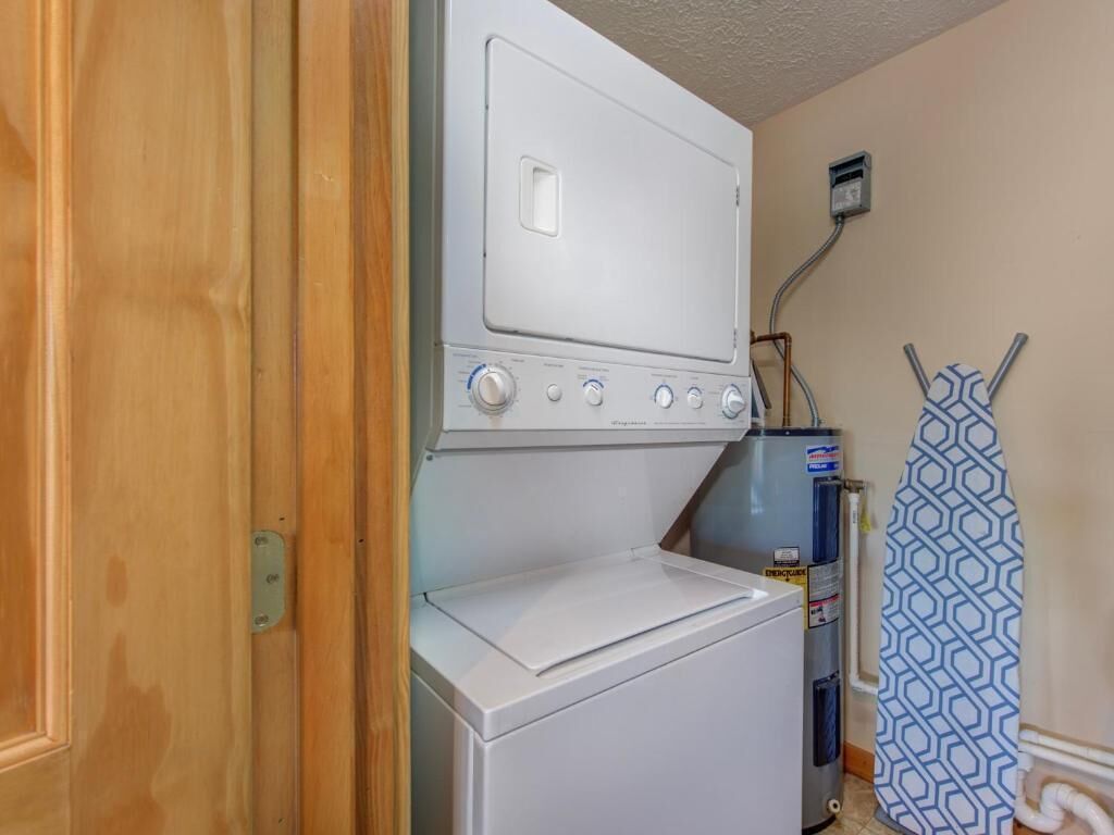 A laundry area with a washer and dryer, a water heater, and an iron board.