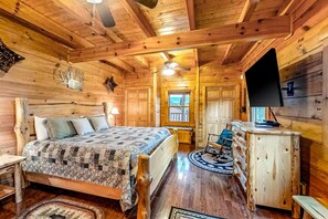 A wooden cabin interior with a bed, dresser, and a television. - Bear Tracks (Sevierville)