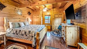 A wooden cabin interior with a bed, dresser, and a television. - Bear Tracks (Sevierville)