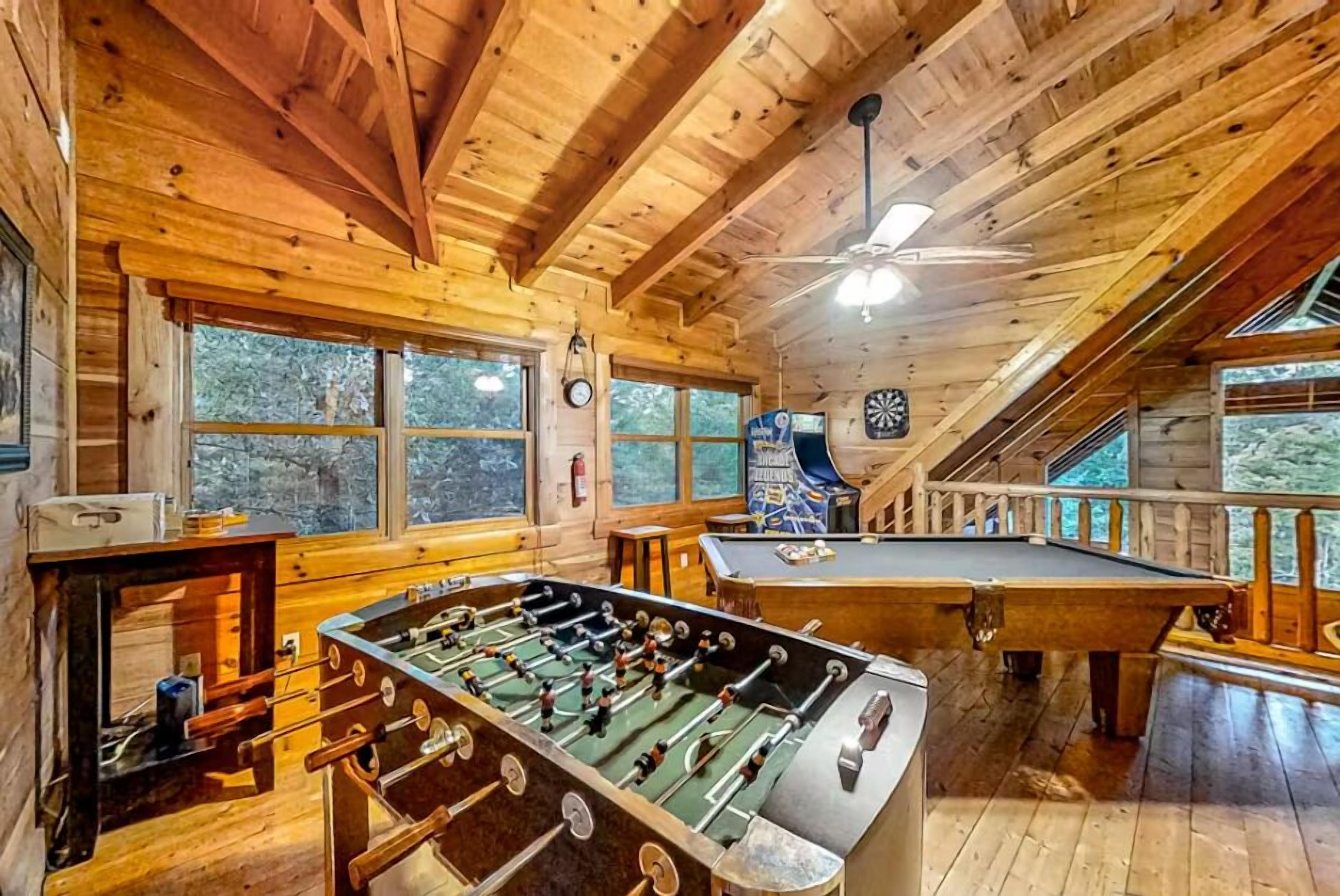 Un intérieur en bois agrémenté d’un baby-foot, d’une table de billard et de grandes fenêtres.