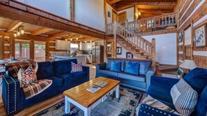 A spacious living area with a high ceiling, wooden beams, and a staircase leading to an upper level. - Mountain Grace Lake Retreat (Sevierville)