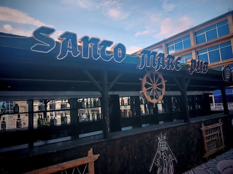 Eine Bar namens 'Sanco Mare Pub' mit einem großen Schild und einer hölzernen Schiffsschwengel-Dekoration.. Santo Mare Hotel & Restaurant