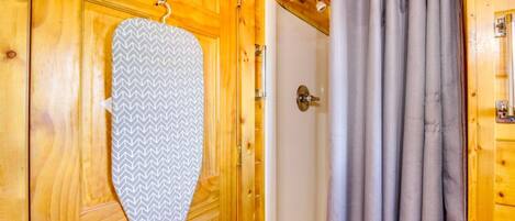 Una puerta de madera con una toalla colgada en un perchero, una cortina de ducha y un cabezal de ducha visible.
