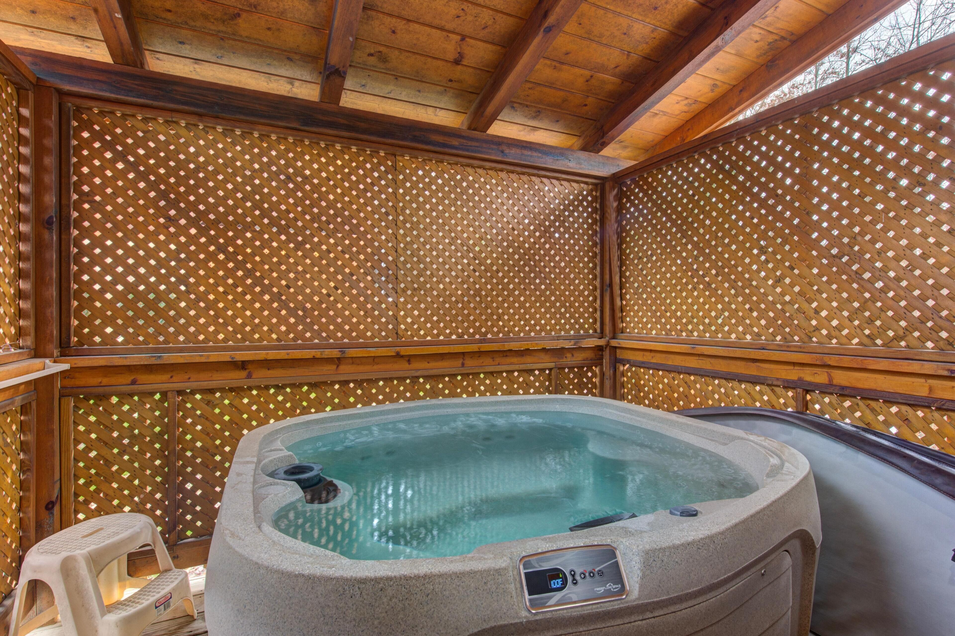 Un bain à remous doté d’un panneau de commande, entouré de murs en treillis de bois et surmonté d’un plafond en bois.