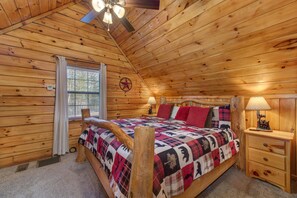 Quarto de cabana de madeira com cama, mesa de cabeceira e janela.