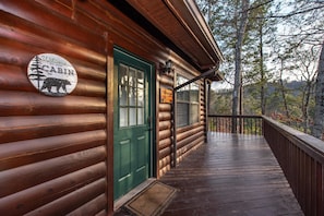 A wooden cabin with a green door, a welcome sign, and a view of trees. - Lil Smoky Mountain Retreat (Sevierville)