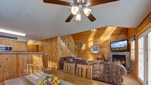 Un intérieur en bois comprenant un coin repas, un canapé, une cheminée et un téléviseur.