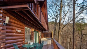 Une cabane en bois dotée d’un balcon, d’un bain à remous et d’une table avec des chaises.