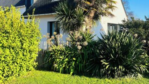 A white house with a sloped roof, surrounded by lush greenery and a well-maintained lawn. - Beachside villa with jacuzzi in Brignogan (Brignogan Plages)