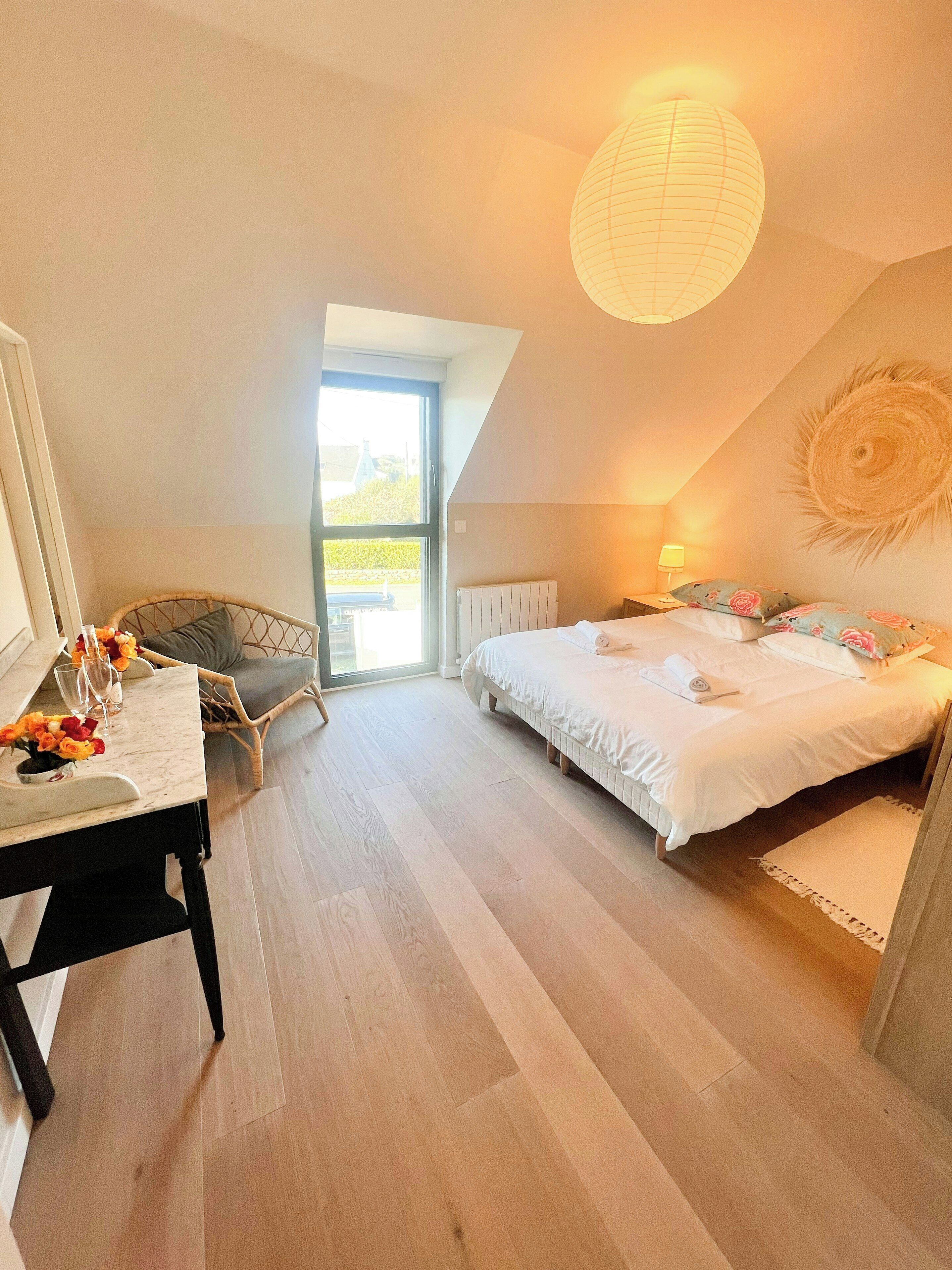 Ein Schlafzimmer mit einem Bett, einem Schreibtisch mit Stuhl, einem Fenster und einer Deckenleuchte.