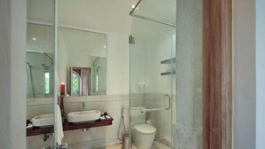 Un baño moderno con cabina de ducha de vidrio, lavamanos doble e inodoro.