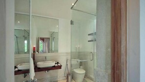 Un bany modern amb boxa de dutxa de vidre, un moble de bany amb doble lavabo i un vàter.
