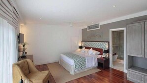 Un dormitorio con cama, mesitas de noche, una silla, armario y zona de ducha.
