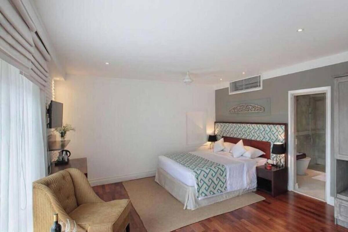 Quarto com cama, mesas de cabeceira, uma cadeira, guarda-roupa e área de chuveiro.