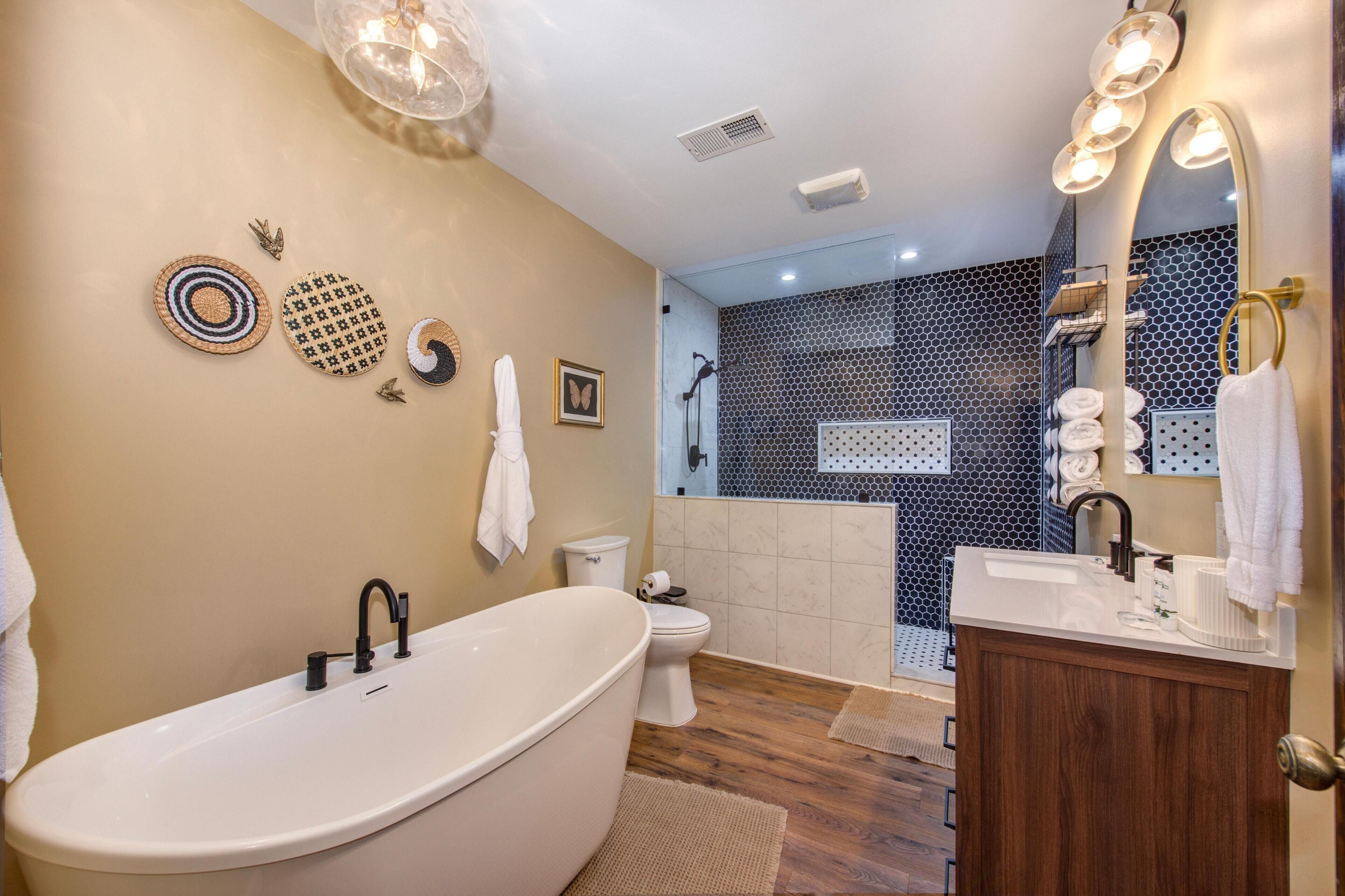 Une salle de bain moderne comprenant une baignoire sur pieds, des toilettes, un espace douche et un meuble-lavabo avec un miroir.