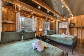 Una cabaña de madera con dos camas, una mesita de noche y una ventana.