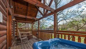 Une terrasse en bois avec un jacuzzi, des rampes en bois et une table de pique-nique.