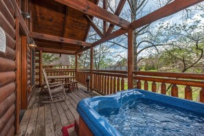 A wooden deck with a hot tub, wooden railings, and a picnic table. - Gods Grace (Pigeon Forge)