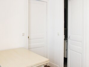 Ein Zimmer mit einer weißen Tür, einer weißen Wand und einem Holztisch.