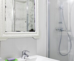 Ein Badezimmer mit Dusche, Waschbecken und einem Fenster mit deutlichen Verschmutzungen.
