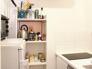 Eine Küche mit Mikrowelle, Wasserkocher und Kaffeemaschine auf der Arbeitsfläche.