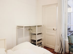 Ein Schlafzimmer mit einem Bett, einem weißen Kleiderschrank und einem Fenster mit Vorhängen.