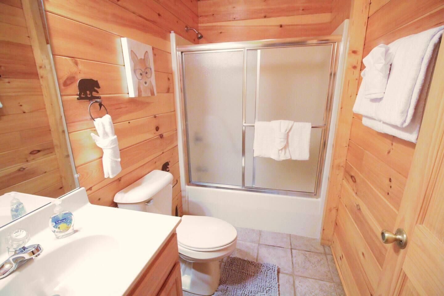 A wooden cabin bathroom with a shower, toilet, and sink.
