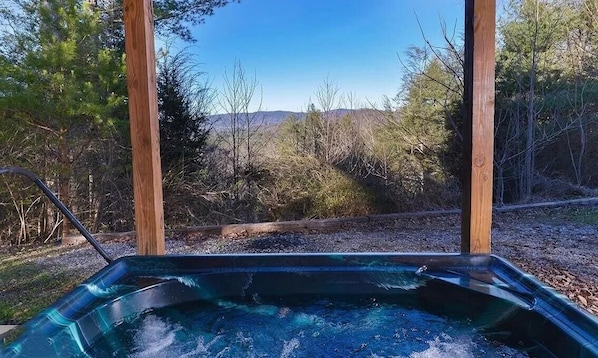 Ein Whirlpool mit Blick auf bewaldetes Gebiet und Hügel im Hintergrund.