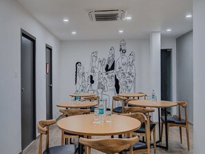 A conference room with round tables, chairs, and a wall mural. - Townhouse Oak T Nagar Chennai (Chennai)