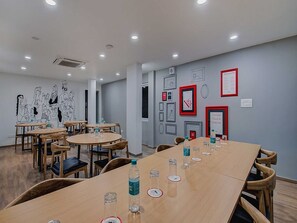 A conference room with round tables, chairs, and a wall with framed pictures and a sign. - Townhouse Oak T Nagar Chennai (Chennai)