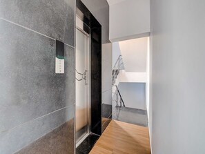 A modern hallway with a glass elevator, a wooden floor, and a staircase. - Townhouse Oak T Nagar Chennai (Chennai)