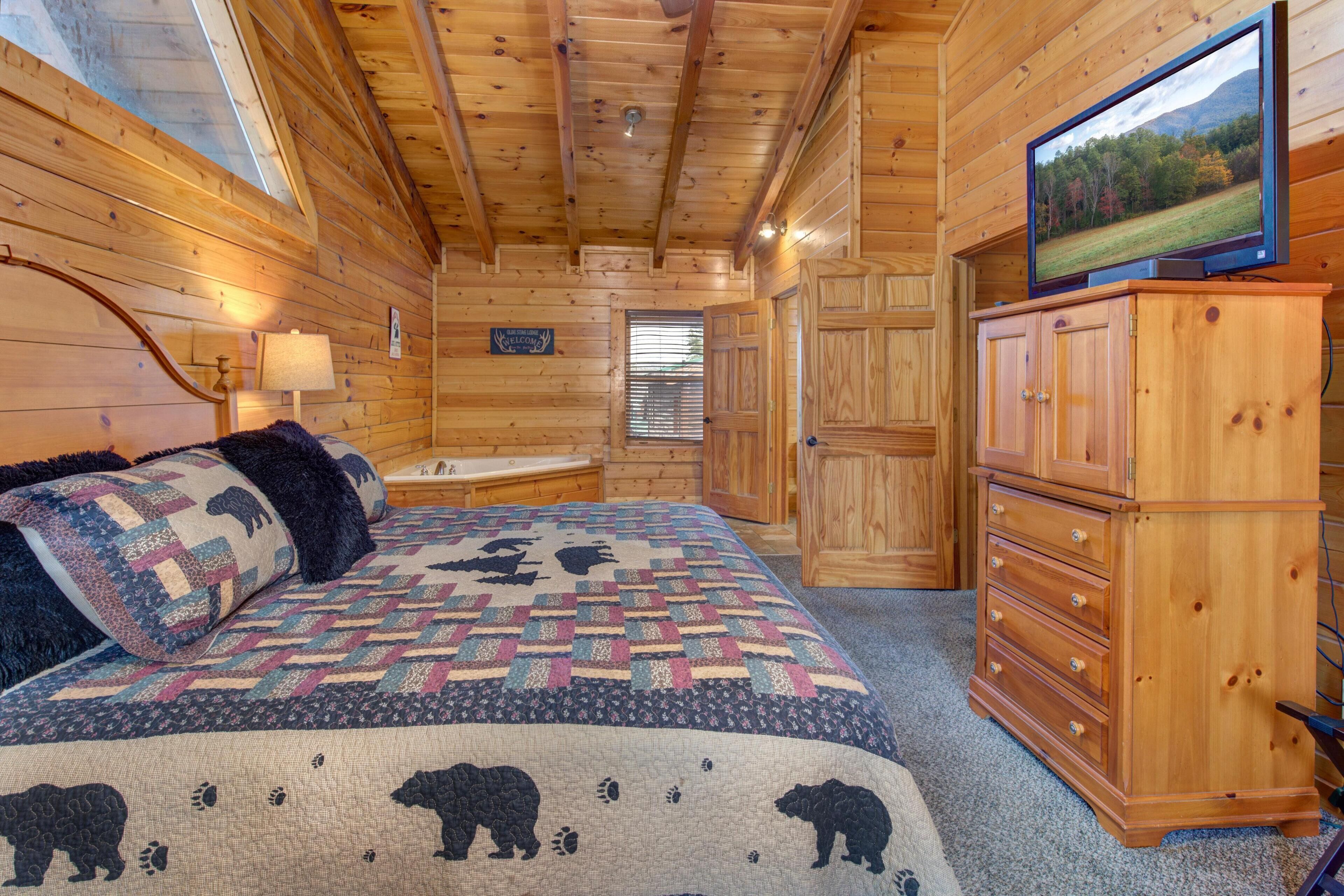 Ein Schlafzimmer in einer Holzhütte mit einem Bett, einem Fernseher, einem Schminktisch und einem Fenster.