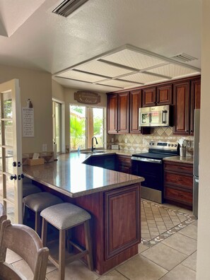 A kitchen with a large island, wooden cabinets, a stainless steel stove, and a microwave. - Relaxing & Spacious Mesa Getaway with pool and hot tub just steps away! (Mesa)