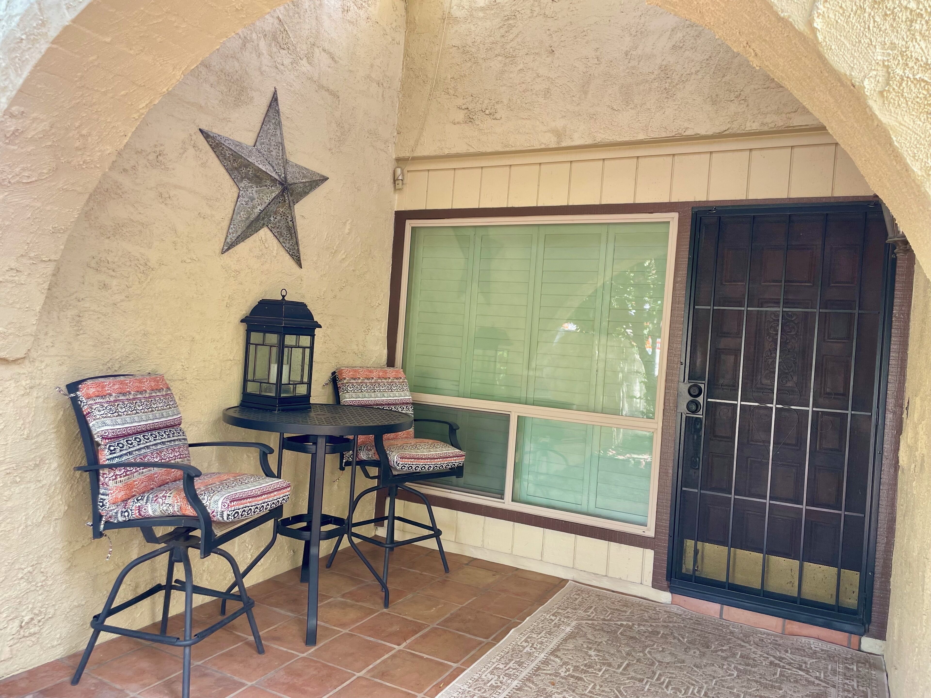 Un espace patio aménagé avec une table et des chaises, une lanterne et une décoration en forme d’étoile.