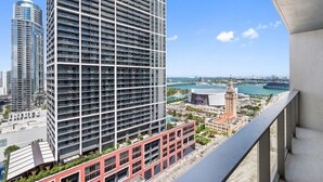 A high-rise building with a grid of windows, a view of the sea, and a distant cityscape. - 501 First #2711 Citylights Elevated Living (Miami)